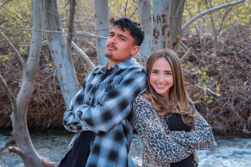 Senior siblings standing back to back by the creek