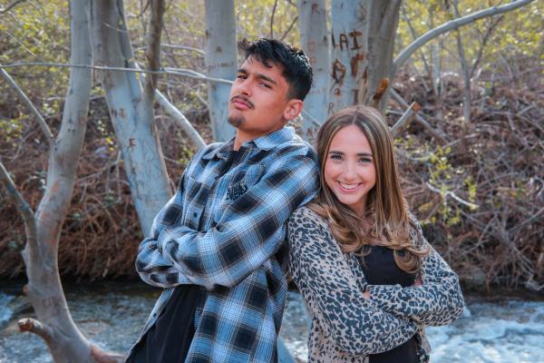 Senior siblings standing back to back by the creek