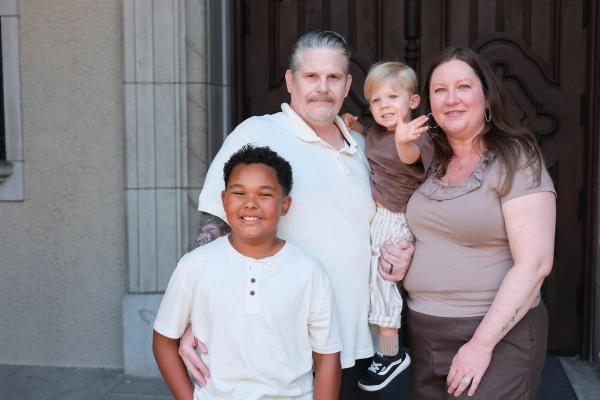 Smiling grandparents holding their grandsons close in front of a stone doorway