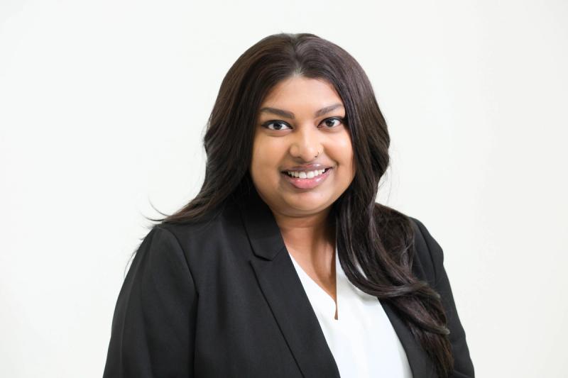 Horizontal studio headshot of a smiling woman in a black blazer