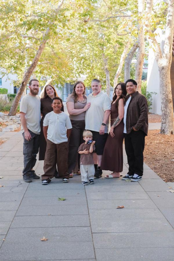 Full-length portrait of the extended family on a long walkway framed by sycamore trees