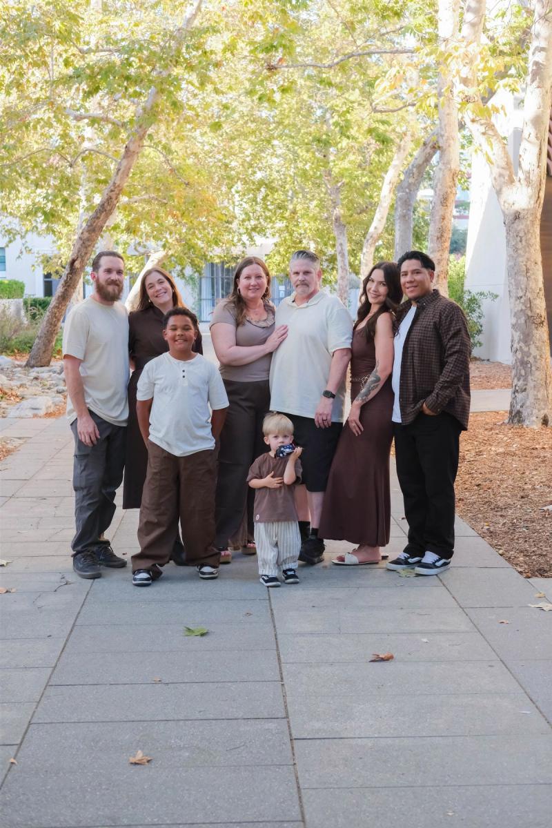 Full-length portrait of the extended family on a long walkway framed by sycamore trees
