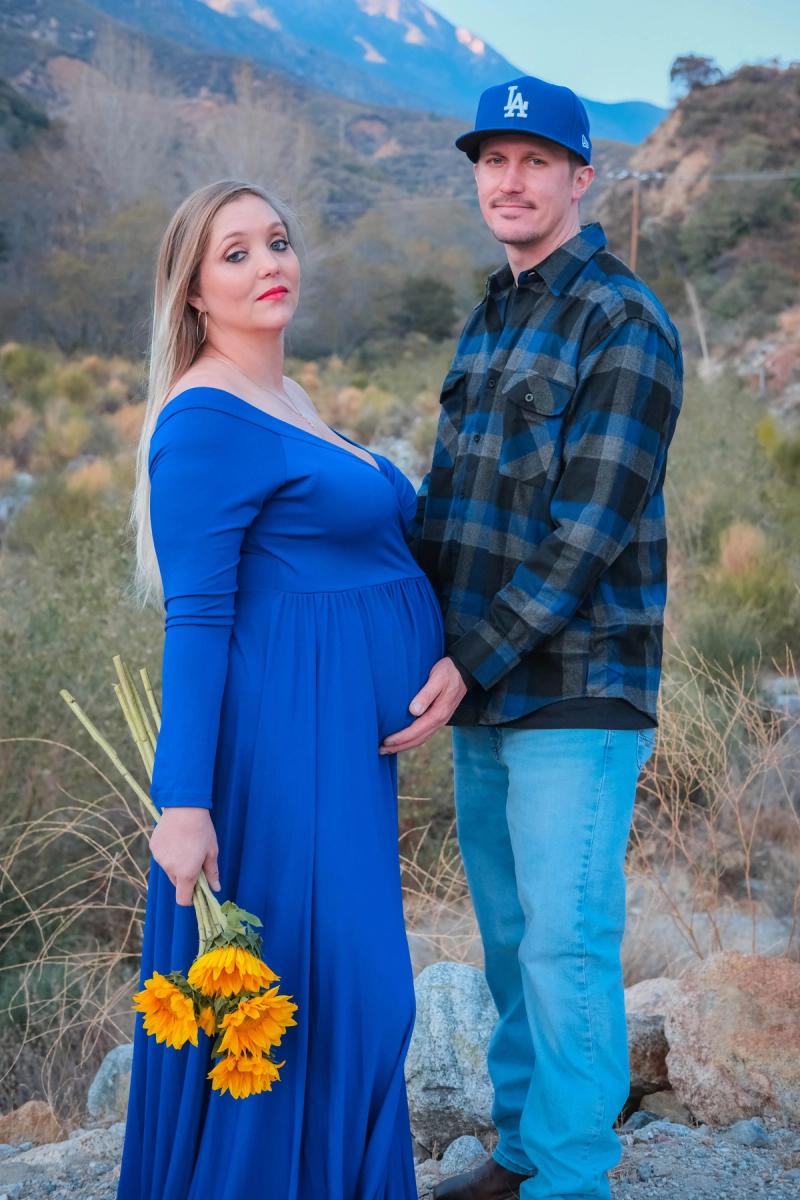 Parents-to-be standing together under a blue sky