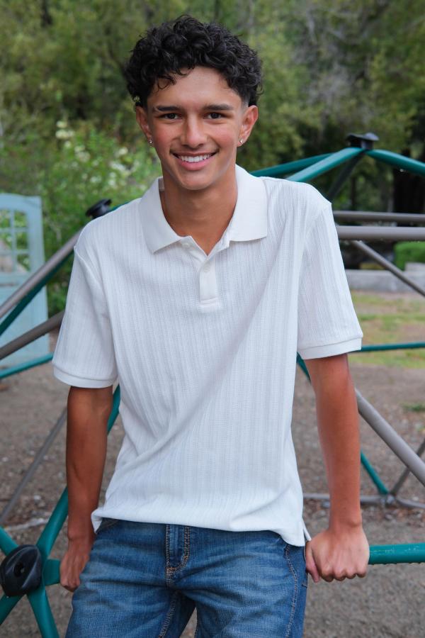 Teen in a white polo smiling on the school playground