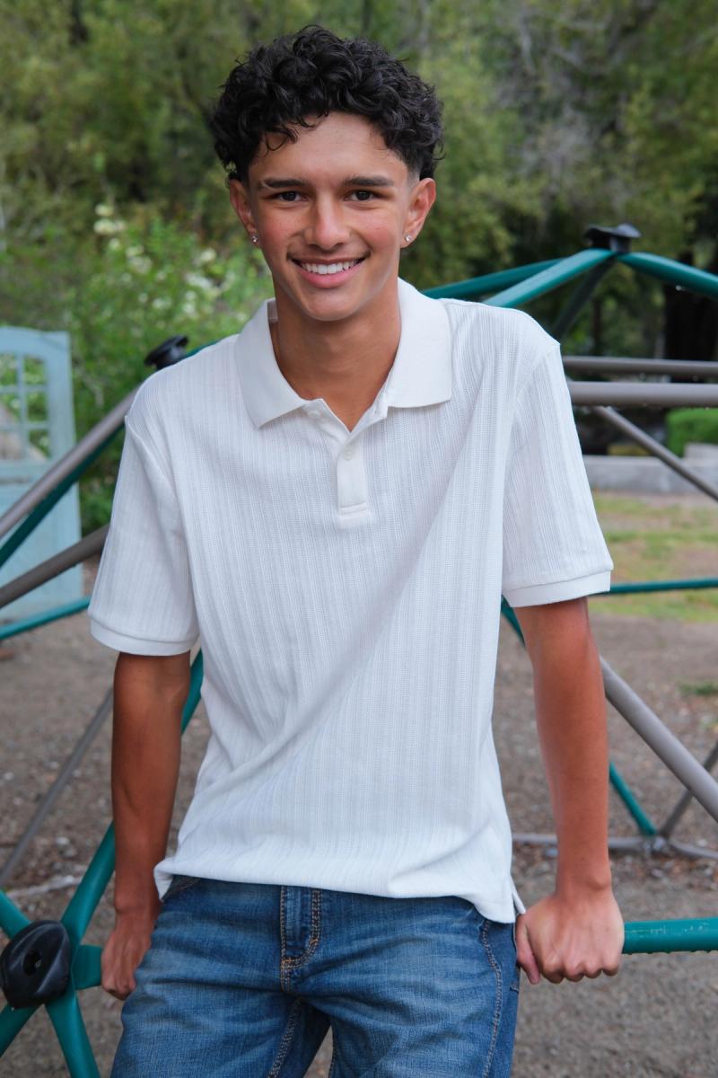Teen in a white polo smiling on the school playground