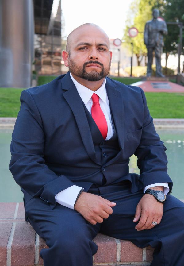 Candidate seated on a ledge in a navy three-piece suit