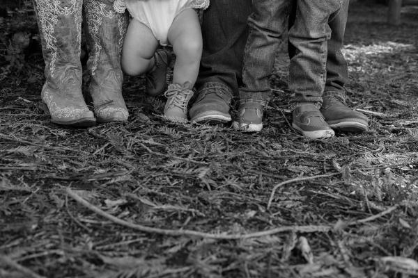 Black and white detail of the family’s boots and little shoes on the forest floor