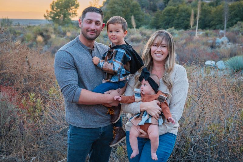 Family of four smiling together in golden light among the trees