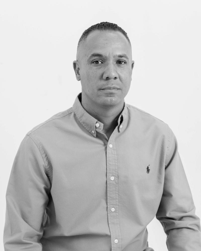 Black and white headshot of a confident man in a button-up shirt