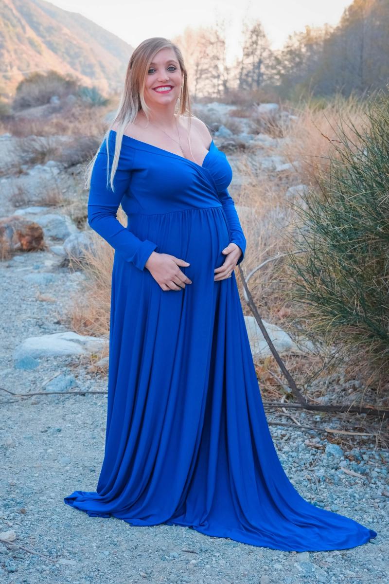 Expecting mother in a flowing royal blue gown on a rocky wash