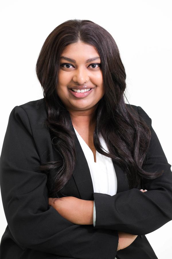 Woman in a black blazer and white blouse with arms crossed, smiling
