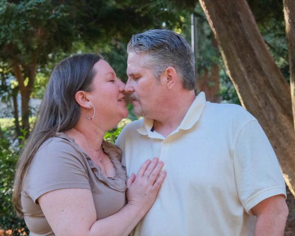 Older couple sharing a tender nose-to-nose moment under the trees