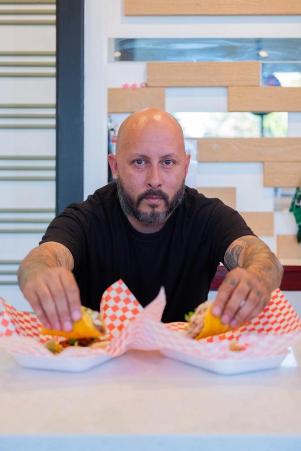 Owner presenting a basket of tacos across the counter