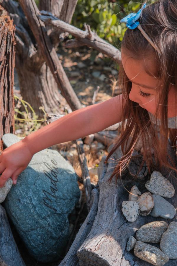 Little girl in a blue bow touching a mossy stone by a garden fountain