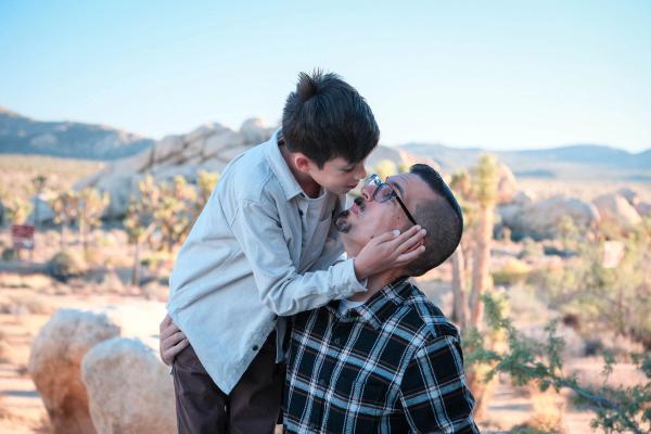Son leaning in to kiss his dad's cheek with the desert behind them
