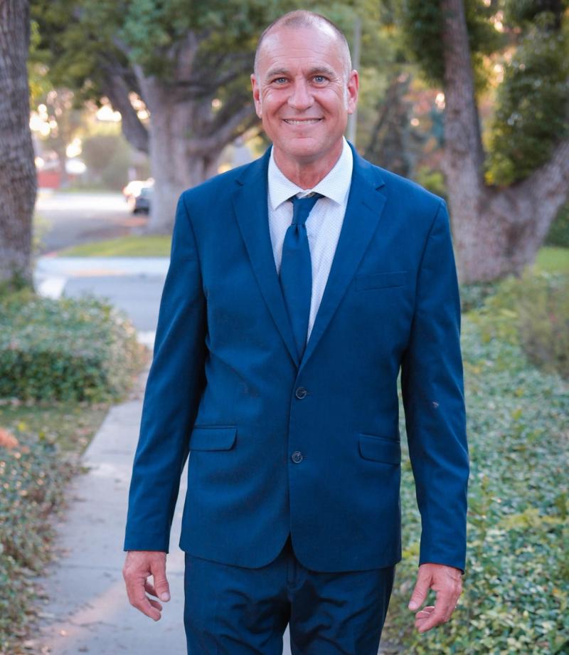 Smiling candidate standing on a hedge-lined path