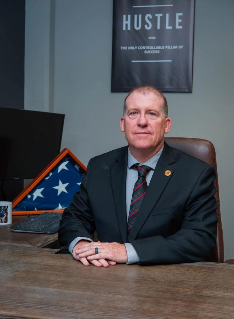 Company leader seated at his desk beside a folded American flag