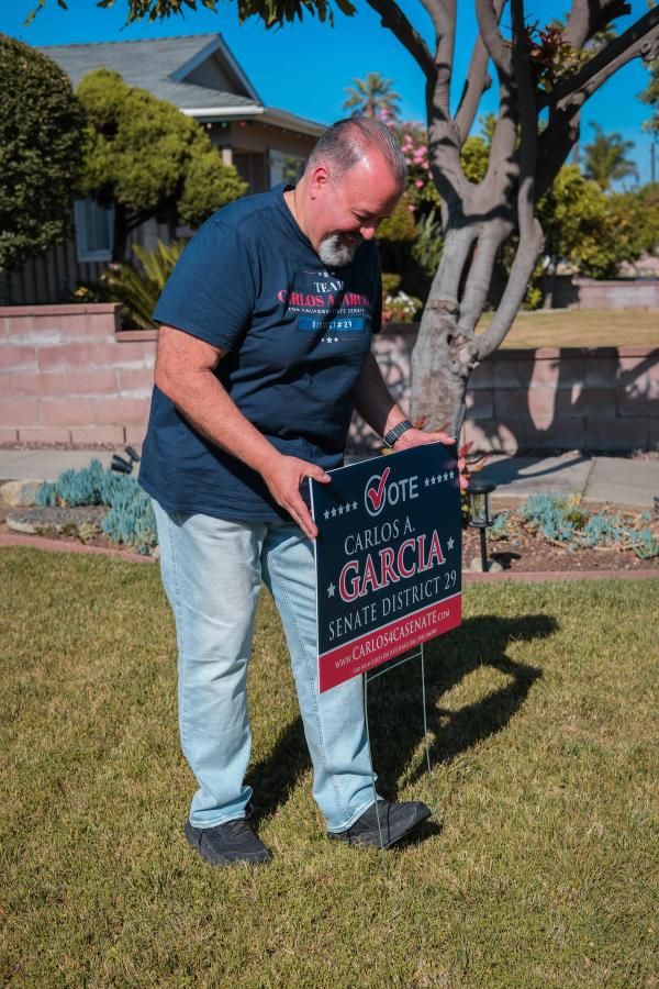 Candidate placing a campaign yard sign on a front lawn