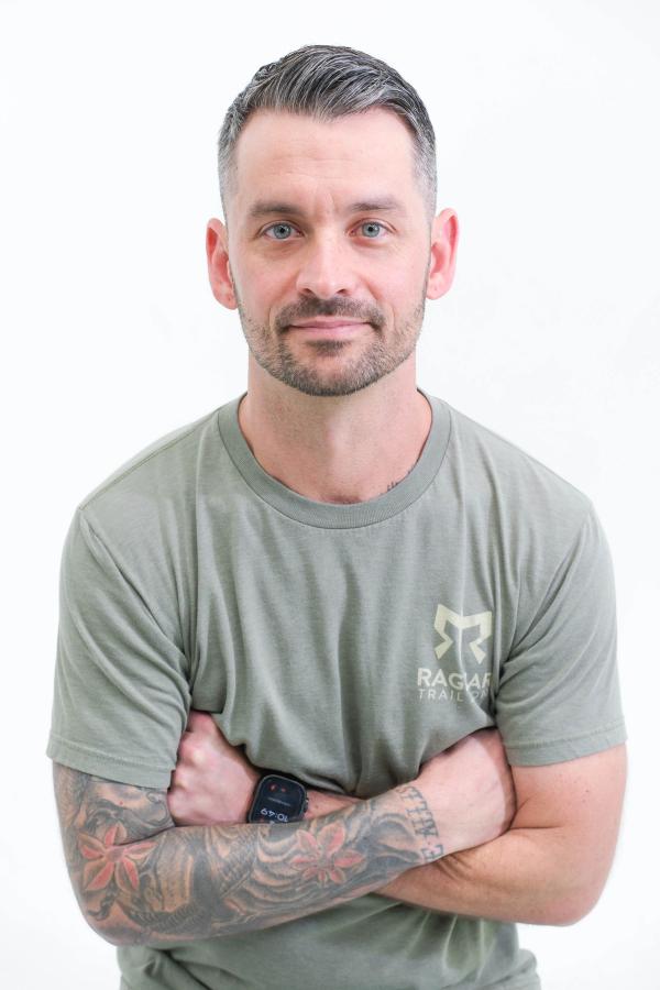 Man in a green T-shirt with arms crossed, relaxed studio portrait