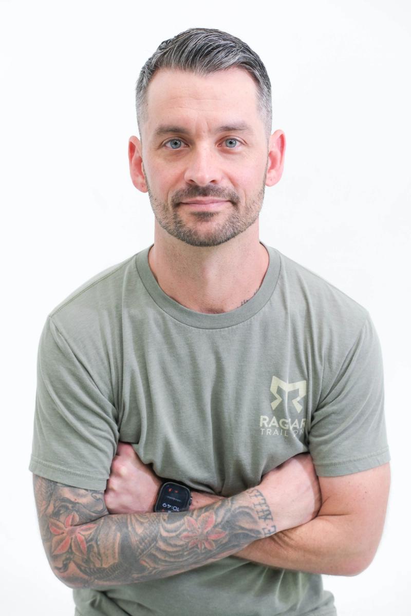 Man in a green T-shirt with arms crossed, relaxed studio portrait