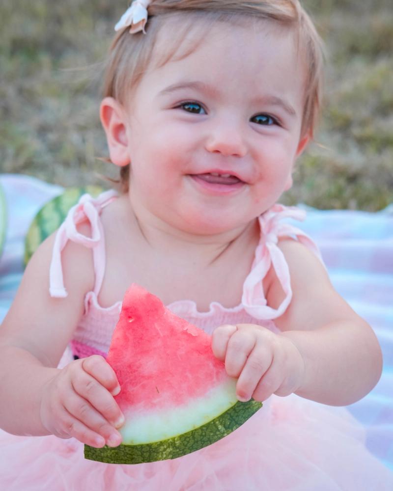 Smiling birthday girl holding a watermelon slice in both hands