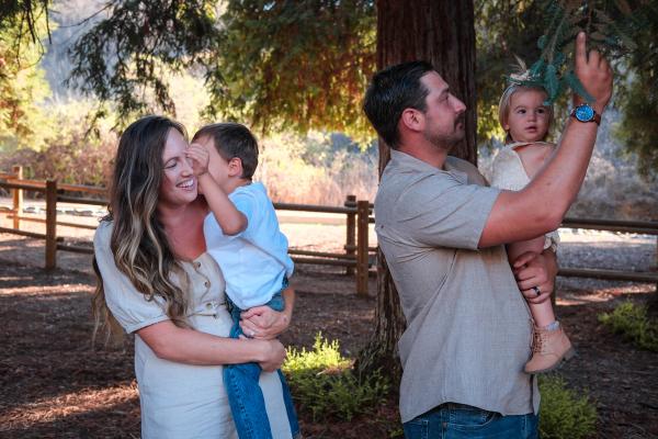 Parents holding their son and baby daughter at a wooded campground