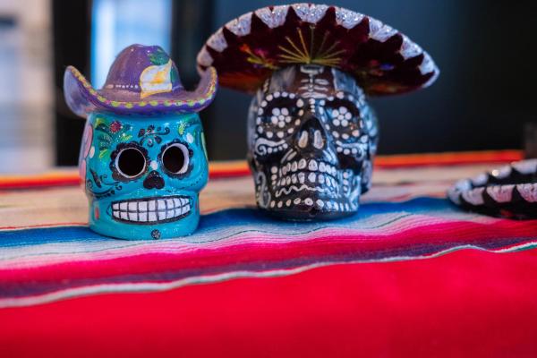 Two painted sugar skulls in tiny sombreros on a serape
