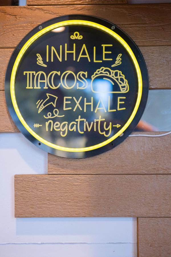 Neon sign reading Inhale Tacos, Exhale Negativity