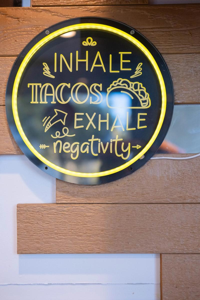 Neon sign reading Inhale Tacos, Exhale Negativity