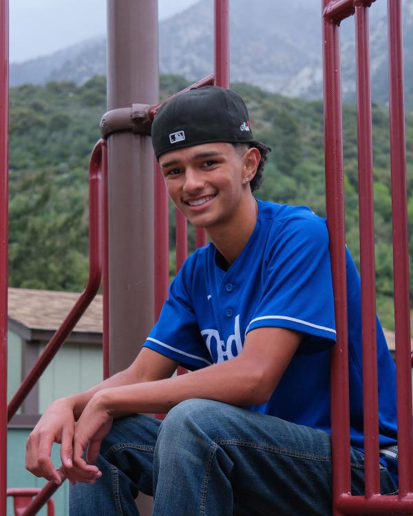 Smiling teen in a backward cap sitting on the playground steps