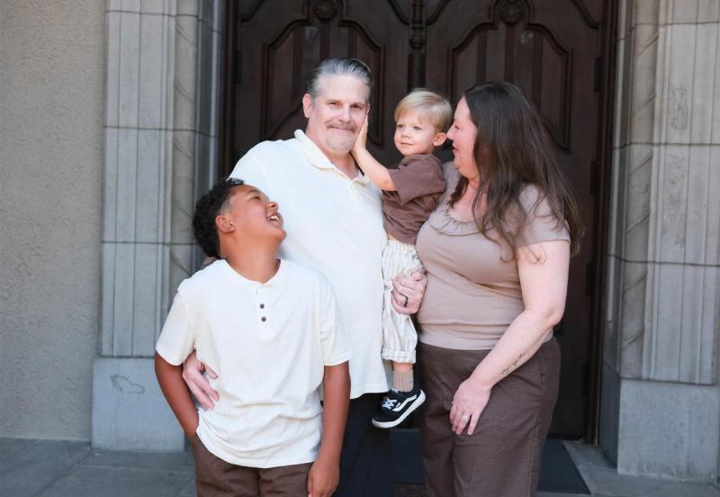 Grandparents laughing with a toddler on hip as their older grandson looks up and grins
