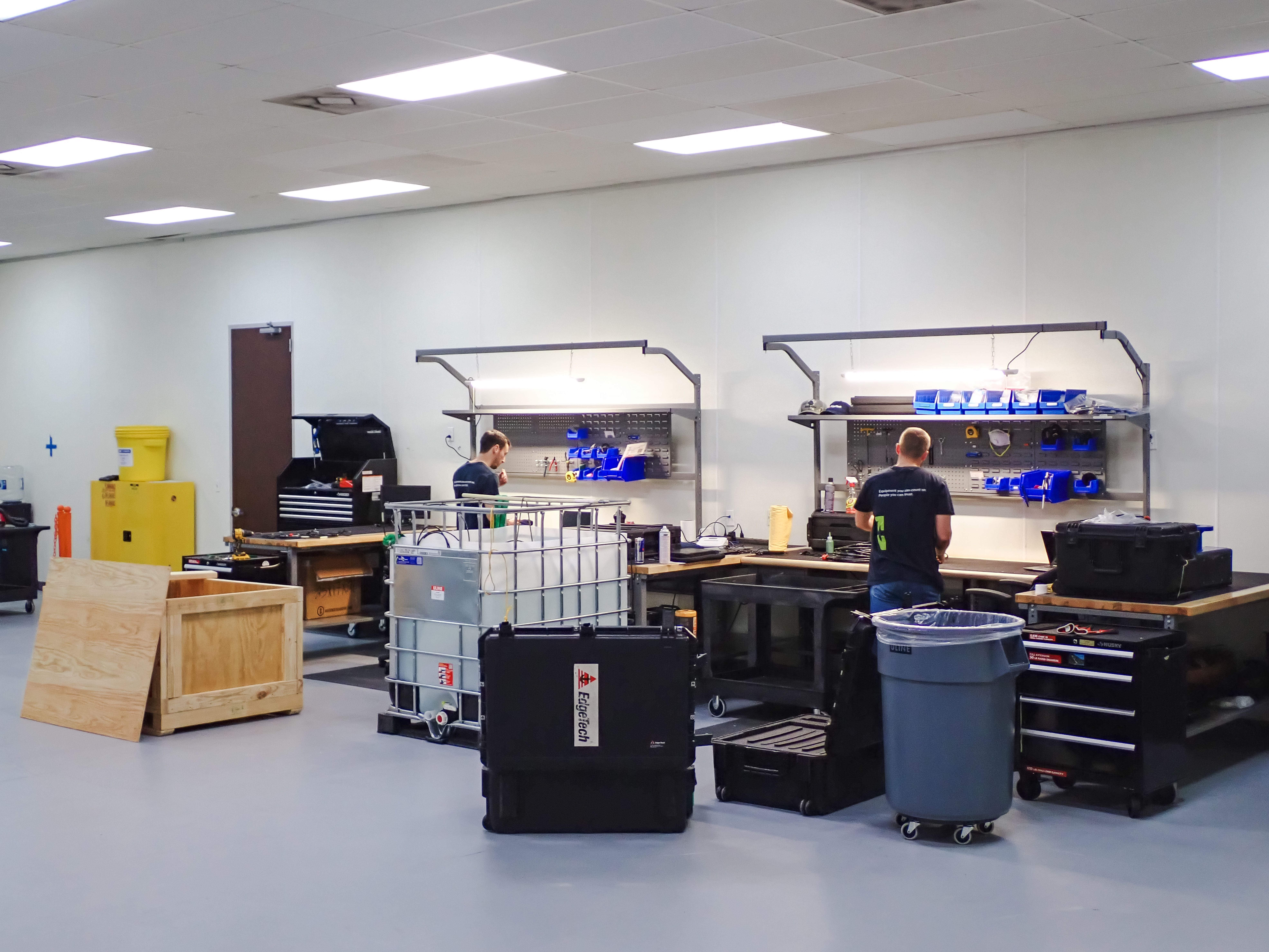 Two men working at separate workstations in a clean industrial workshop.