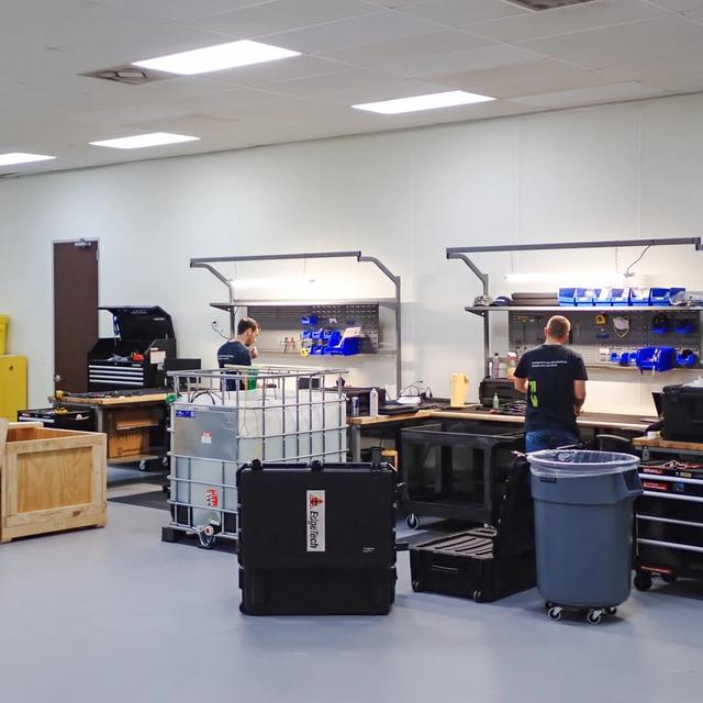 Two men working at separate workstations in a clean industrial workshop.