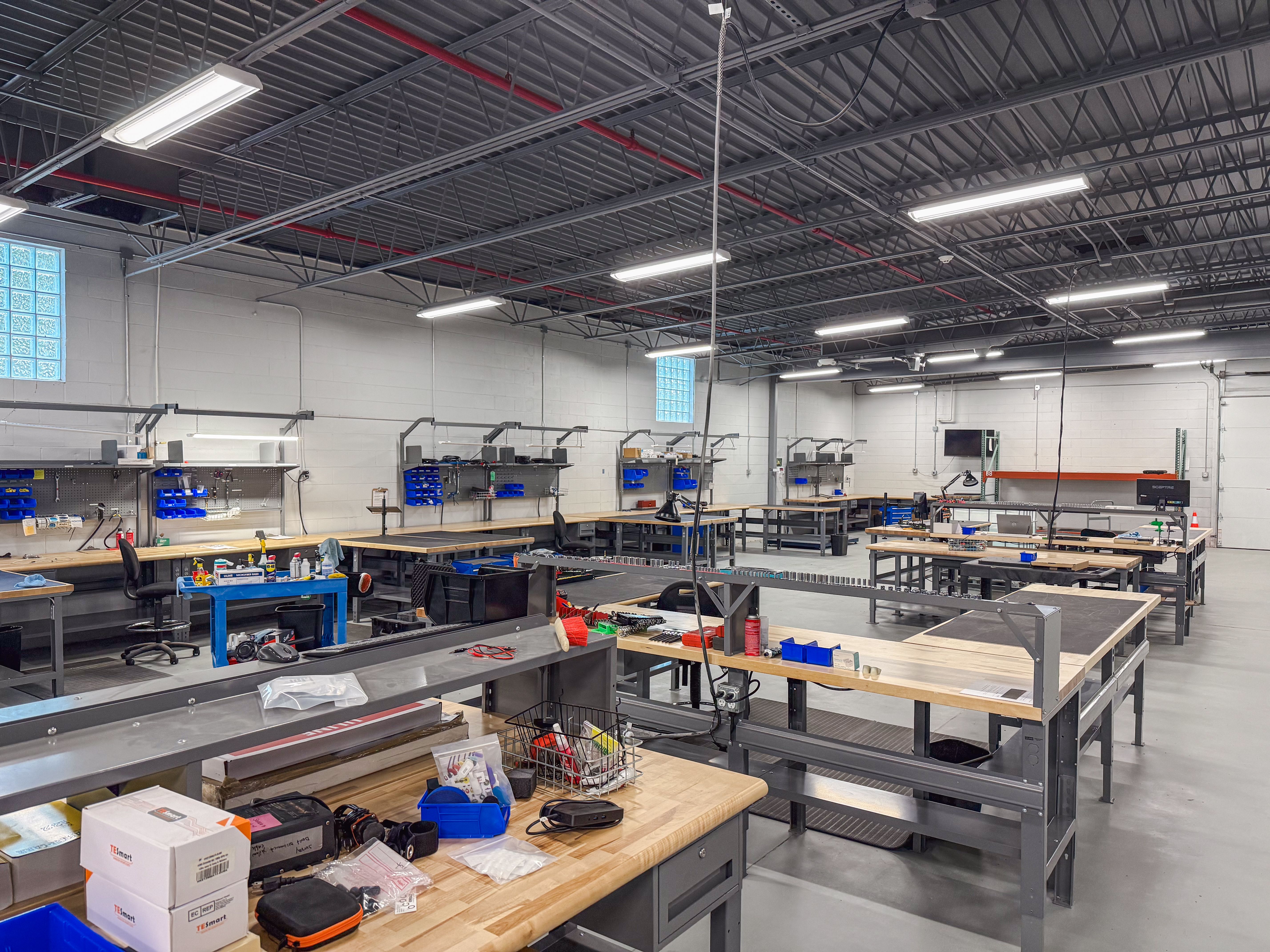 Spacious, clean workshop with multiple workbenches, tools, and equipment.
