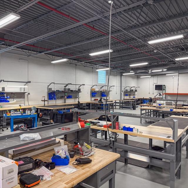 Spacious, clean workshop with multiple workbenches, tools, and equipment.