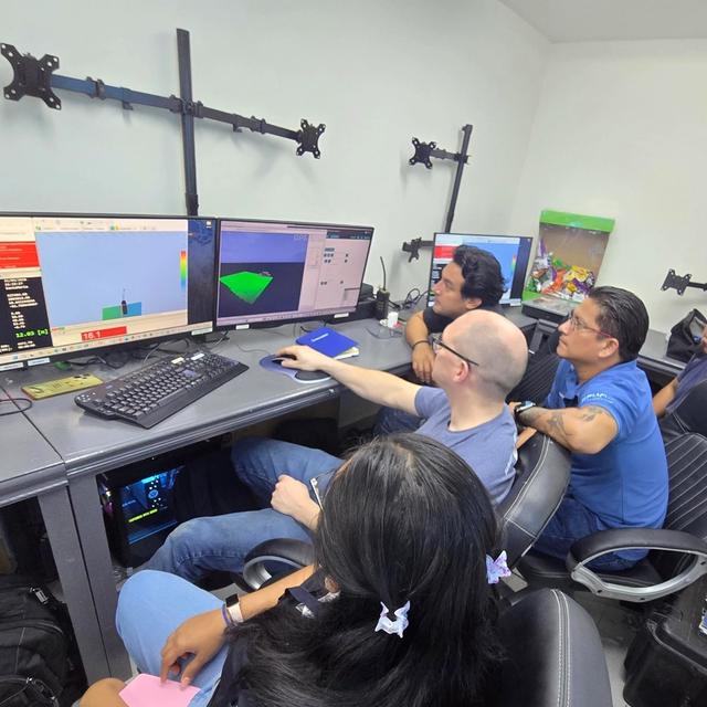 A diverse group of six people intently watches multiple computer screens displaying rocket simulations and data.