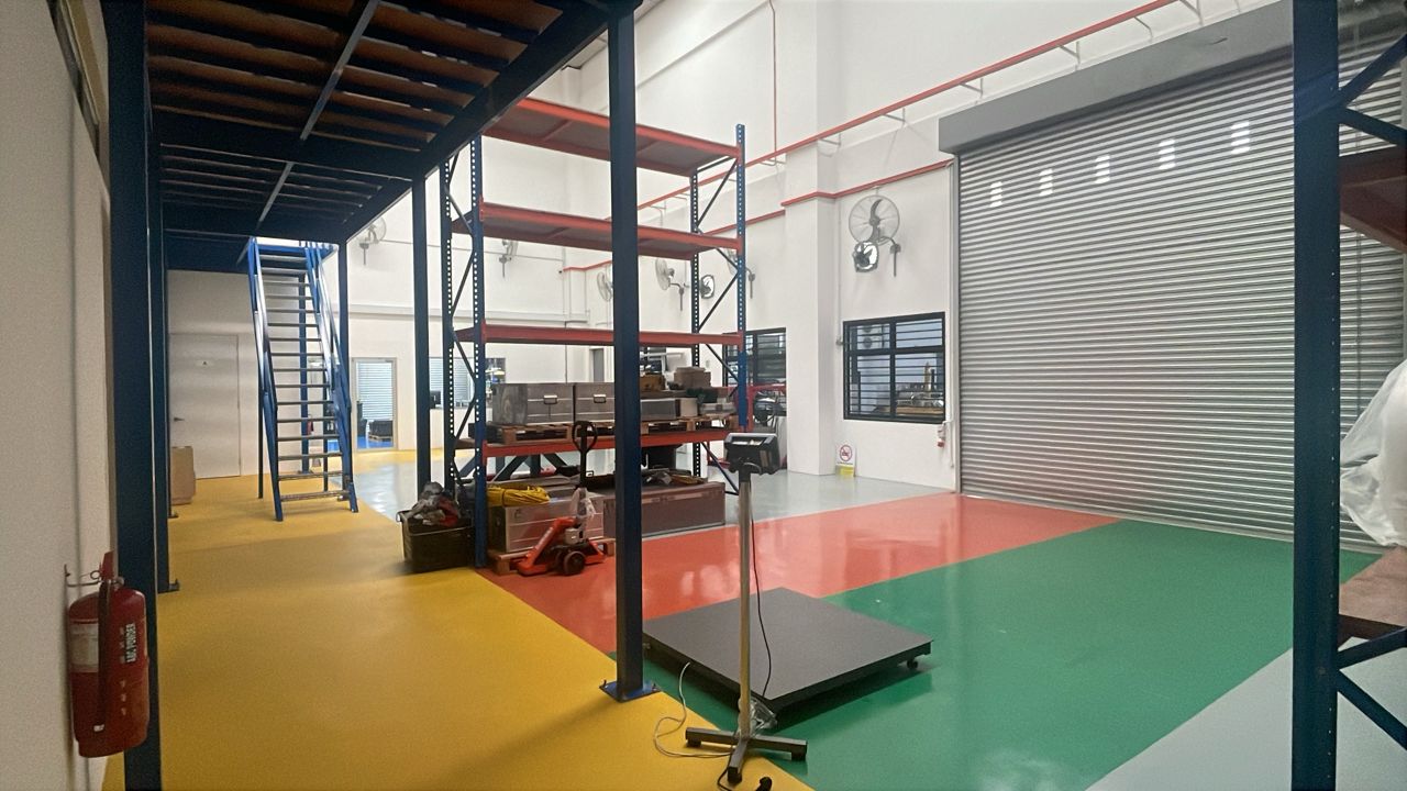 Clean industrial space with a mezzanine, metal shelving, a large roll-up door, and a colorful floor.
