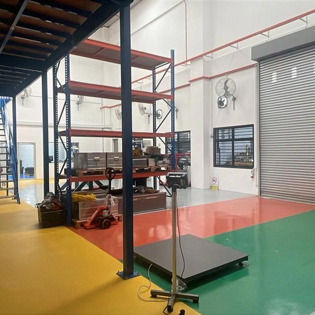 Clean industrial space with a mezzanine, metal shelving, a large roll-up door, and a colorful floor.