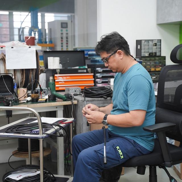 A man works with components at a workshop bench.