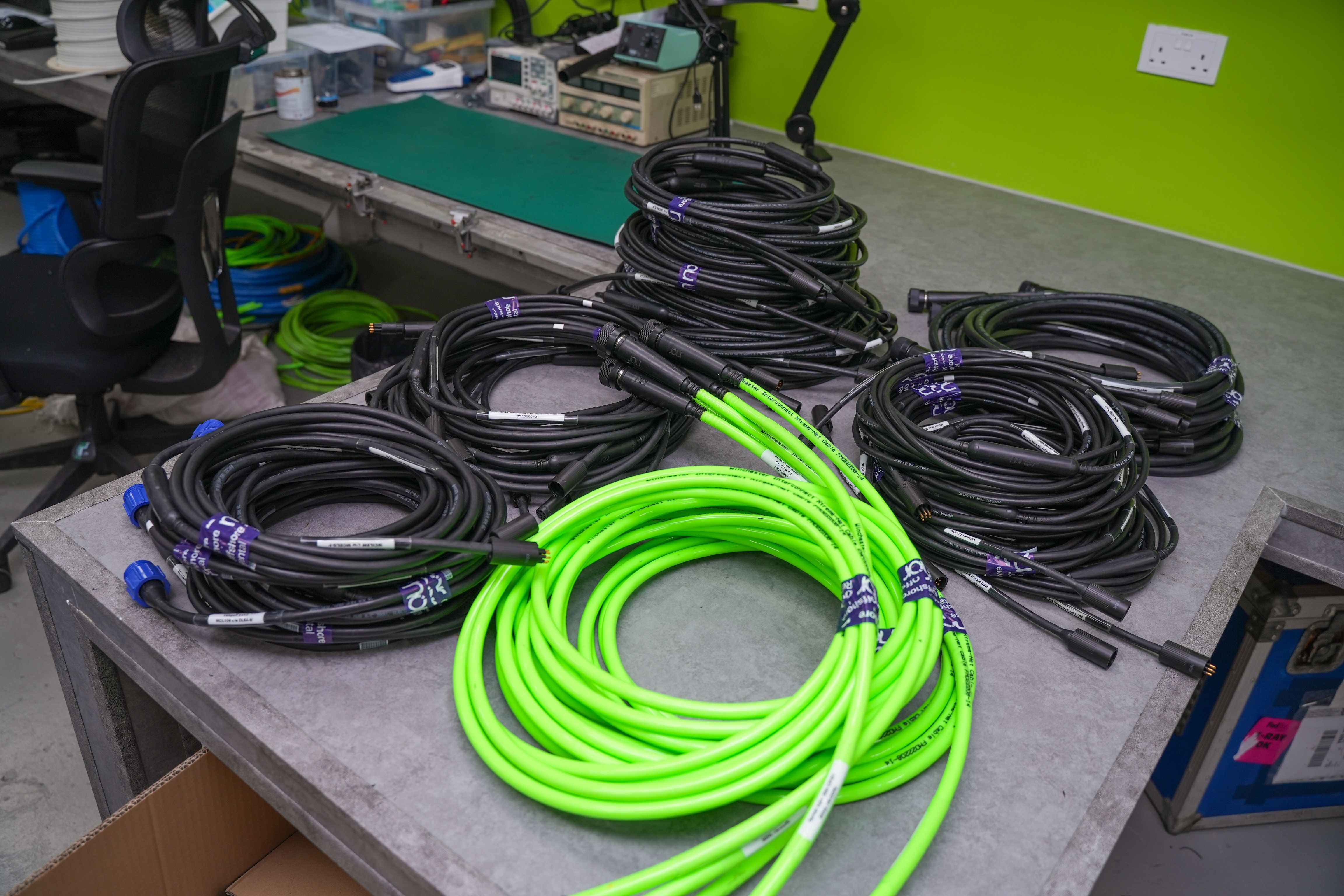 Stacks of coiled black and neon green cables on a workbench.