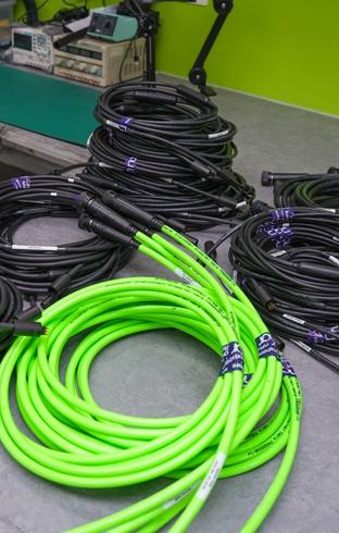 Stacks of coiled black and neon green cables on a workbench.