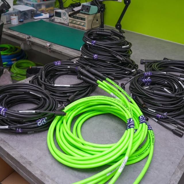 Numerous coiled black and bright green cables on a workbench.