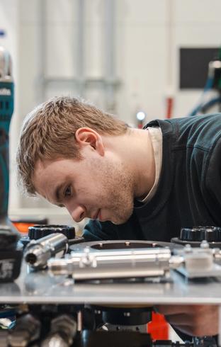 Young man intently examining mechanical equipment.