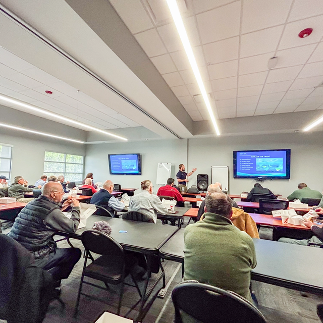 A group of adults attends a presentation in a conference room.