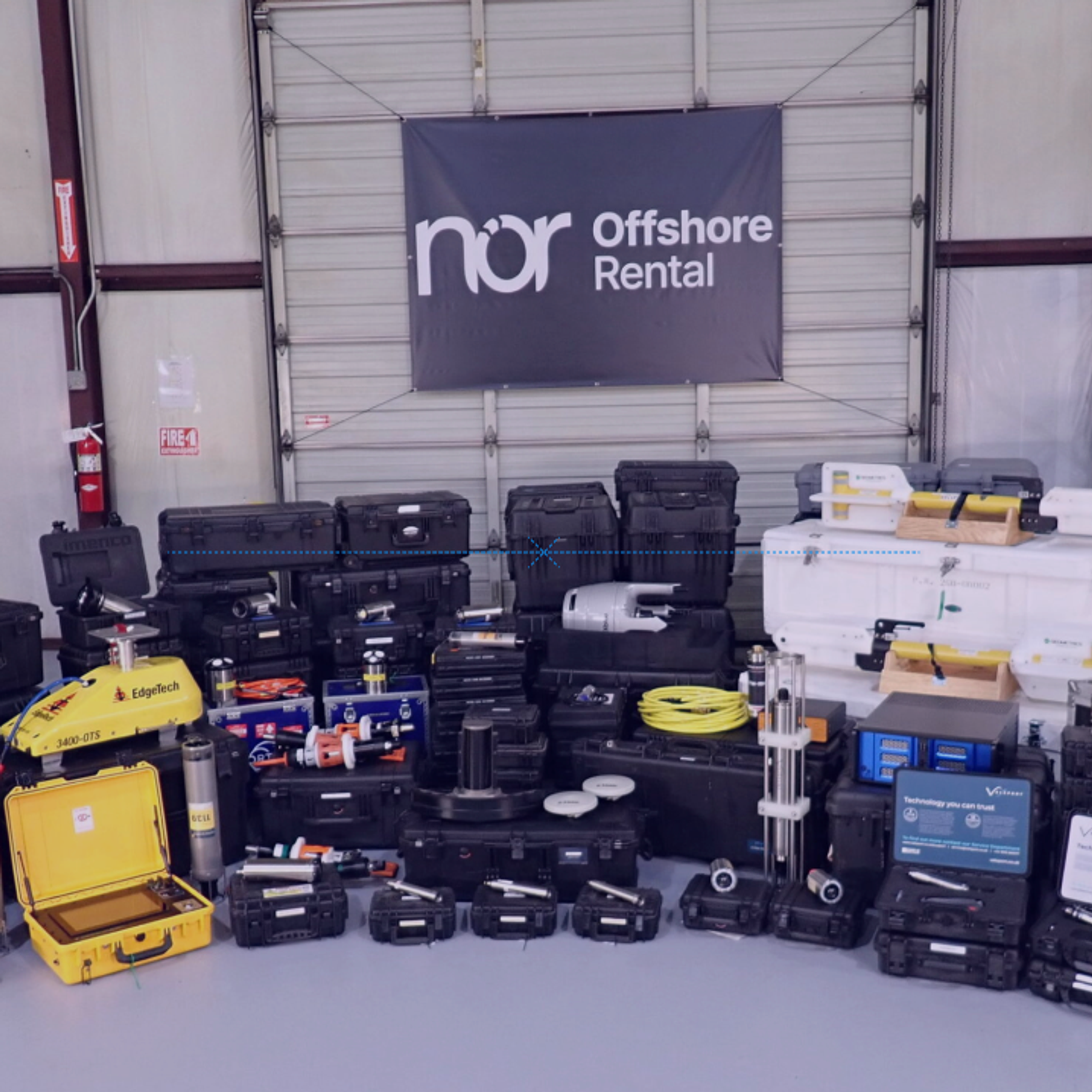 A wide array of black, yellow, and white offshore rental equipment displayed in a warehouse beneath a "nor Offshore Rental" banner.