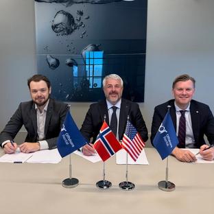 Three men in suits sign documents at a table with small flags of Norway, USA, and Offshore Rental.