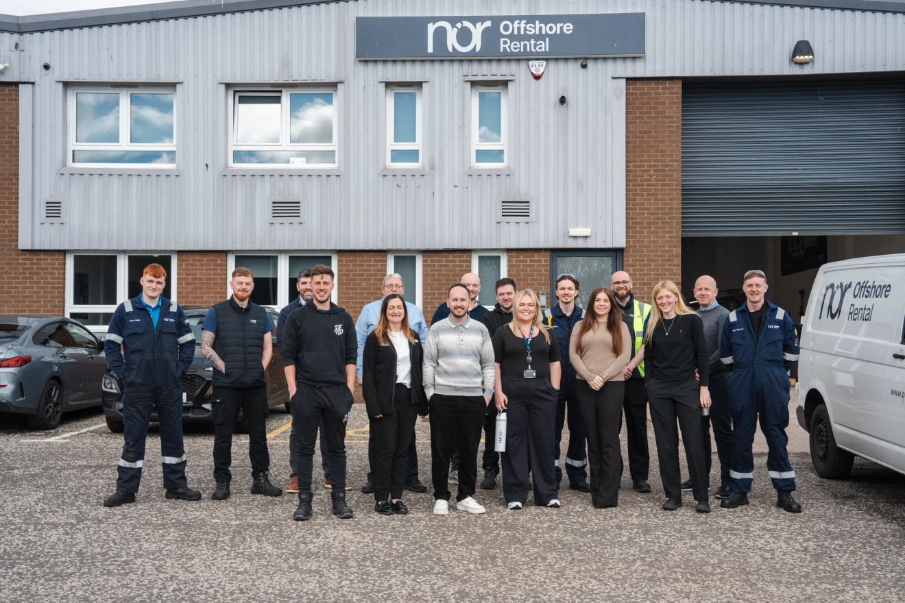 Group photo of NOR staff in front of their company building and a branded van.