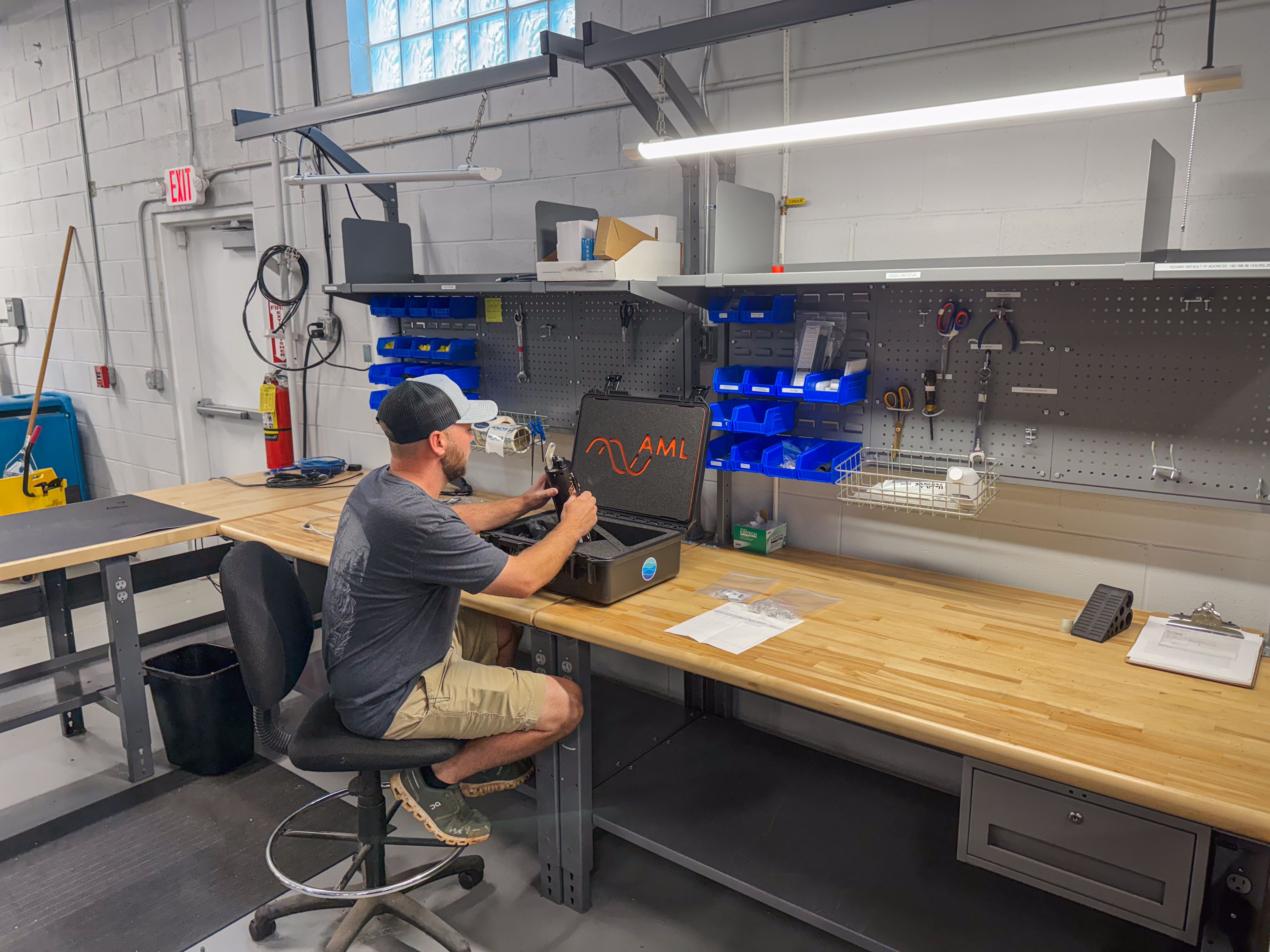 A man works on equipment from an open case at a workshop bench.