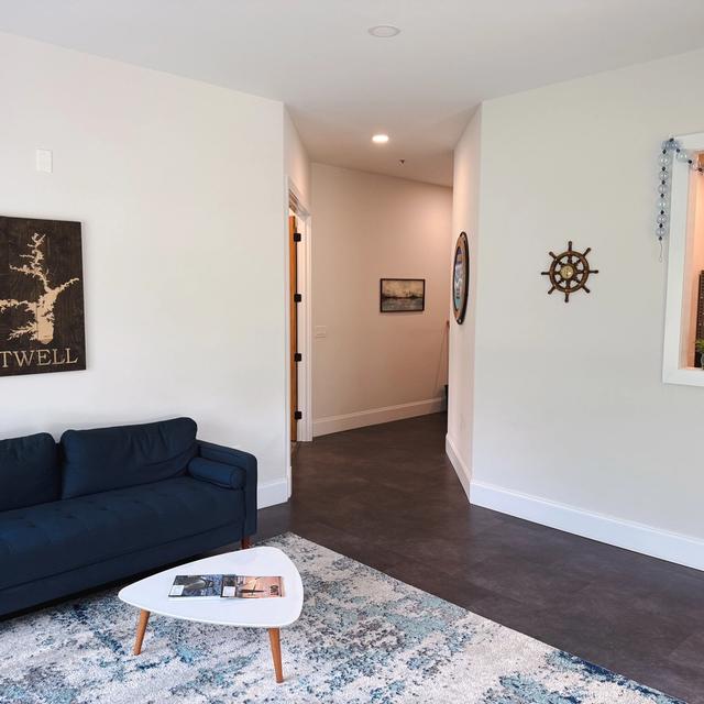 A waiting area with a blue sofa, Lake Hartwell map, ship's wheel decor, and a window to a reception desk.