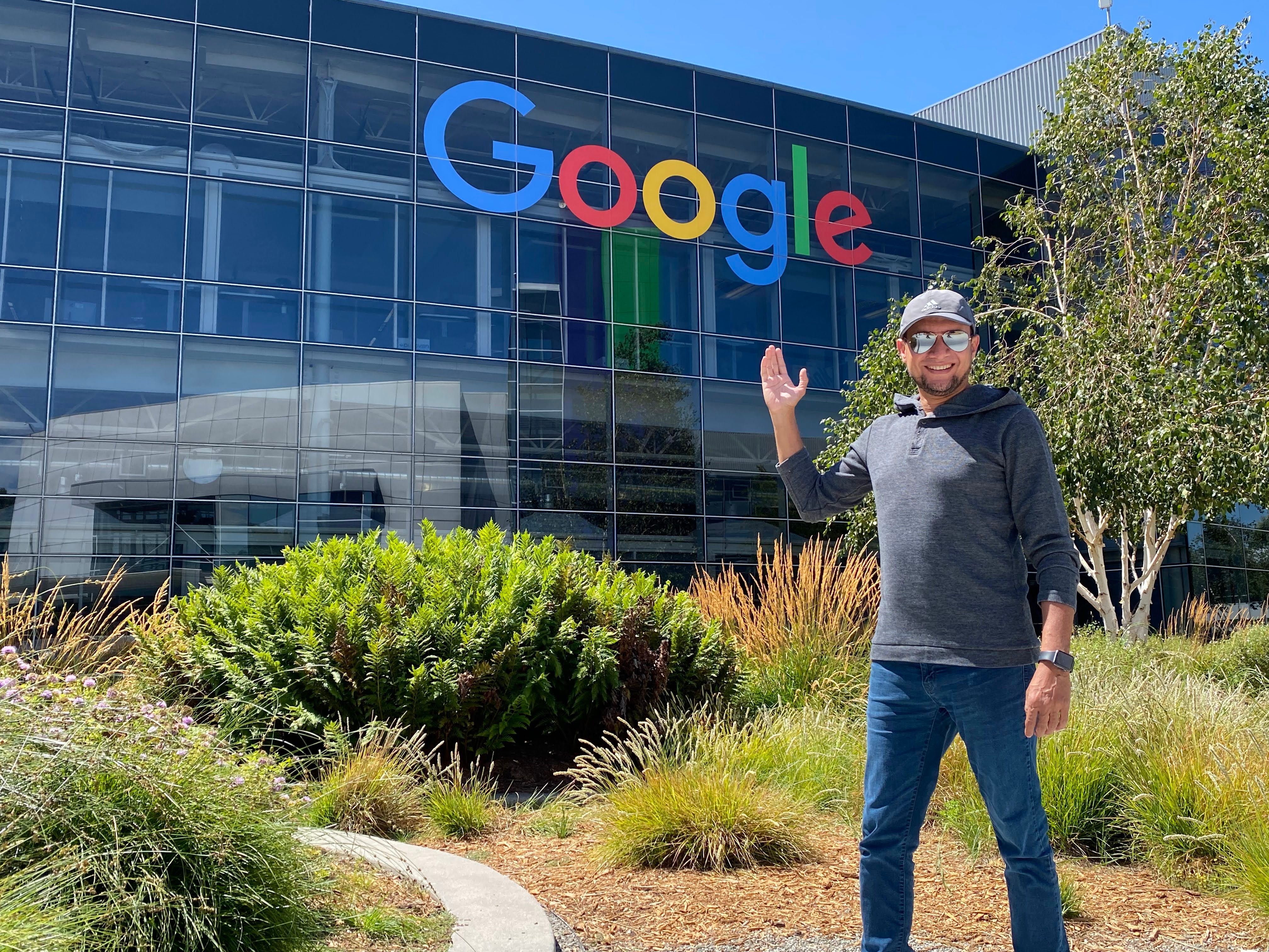 A man waves in front of the Google building.